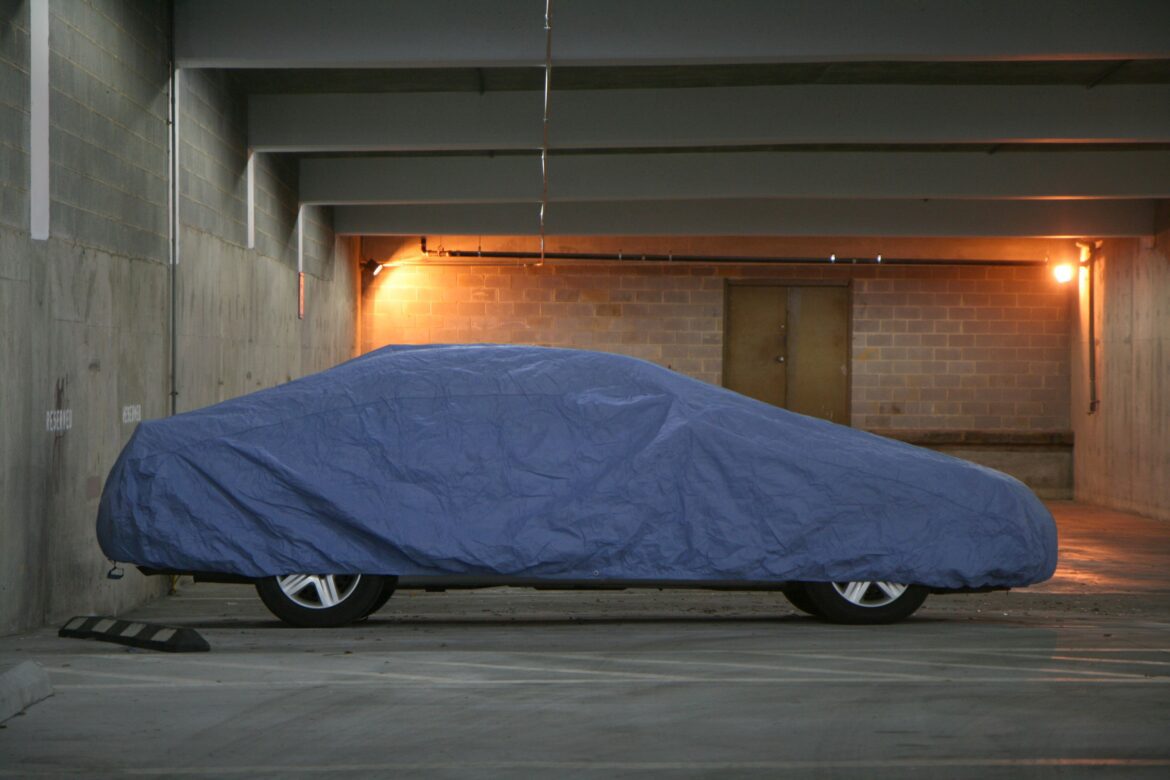 Odstavené auto pod plachtou v parkovací garáži.