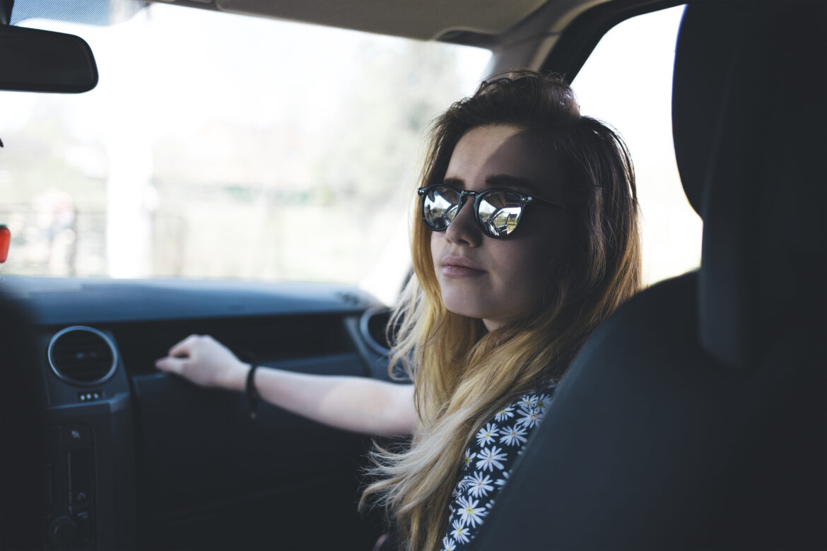 Cestující se slunečními brýlemi v interiéru automobilu.