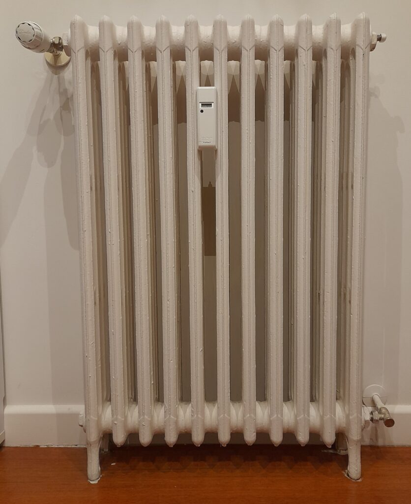 Radiátor s termostatickou hlavicí a elektronickým rozdělovačem nákladů na teplo.