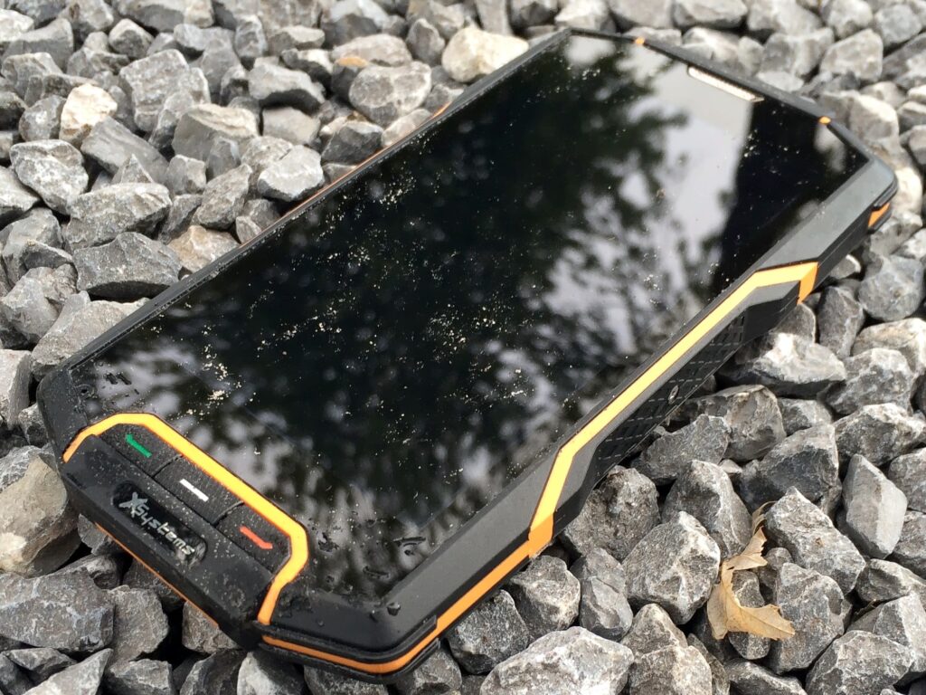 Odolný chytrý telefon položený na kamenech.