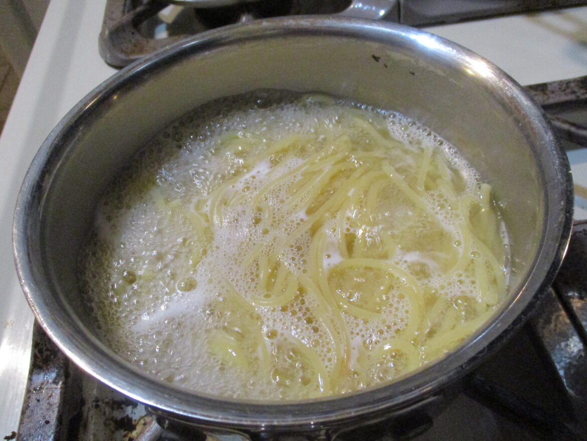 Špagety vařící se ve vodě v kovovém hrnci. Fotografie do textu: Spaghetti draining.jpg