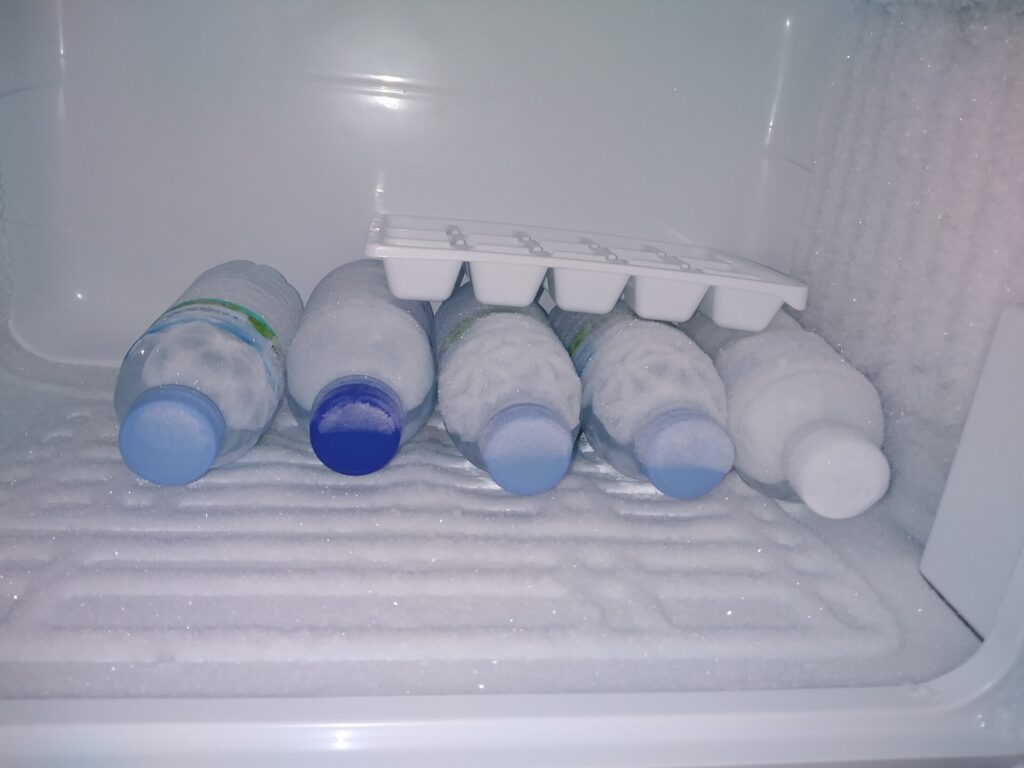 Lahve s vodou a tvořítko na kostky ledu v mrazáku.