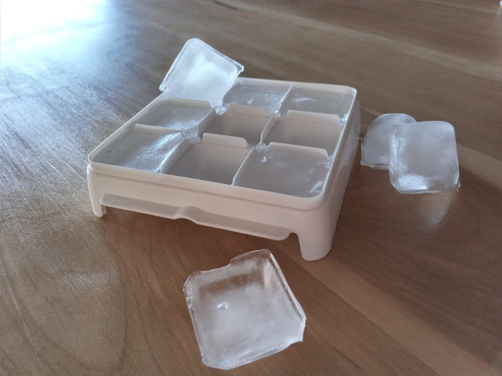 Tvořítko na led a vysypané kostky ledu.