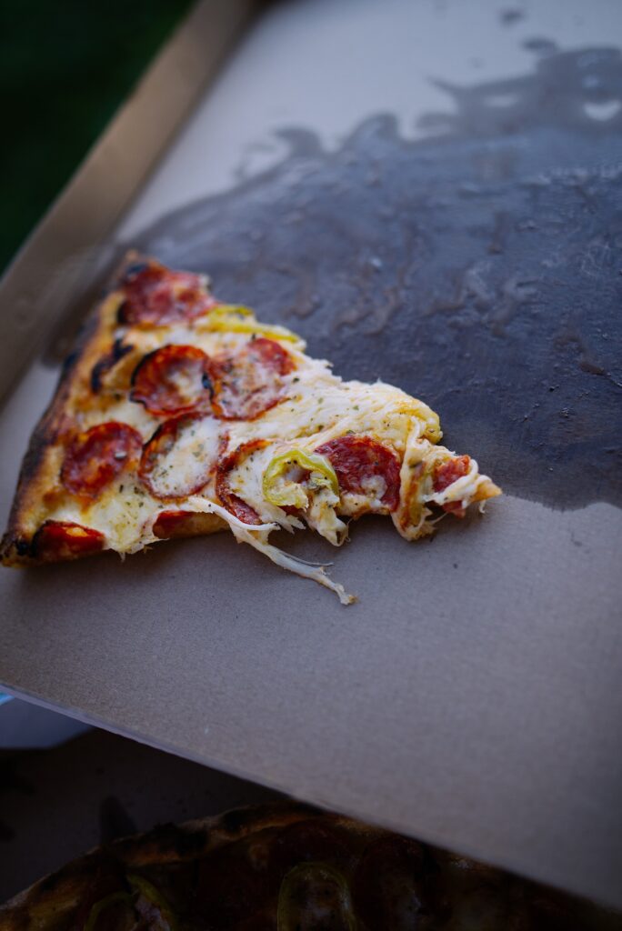 Poslední dílek pizzy v otevřené kartonové krabici.