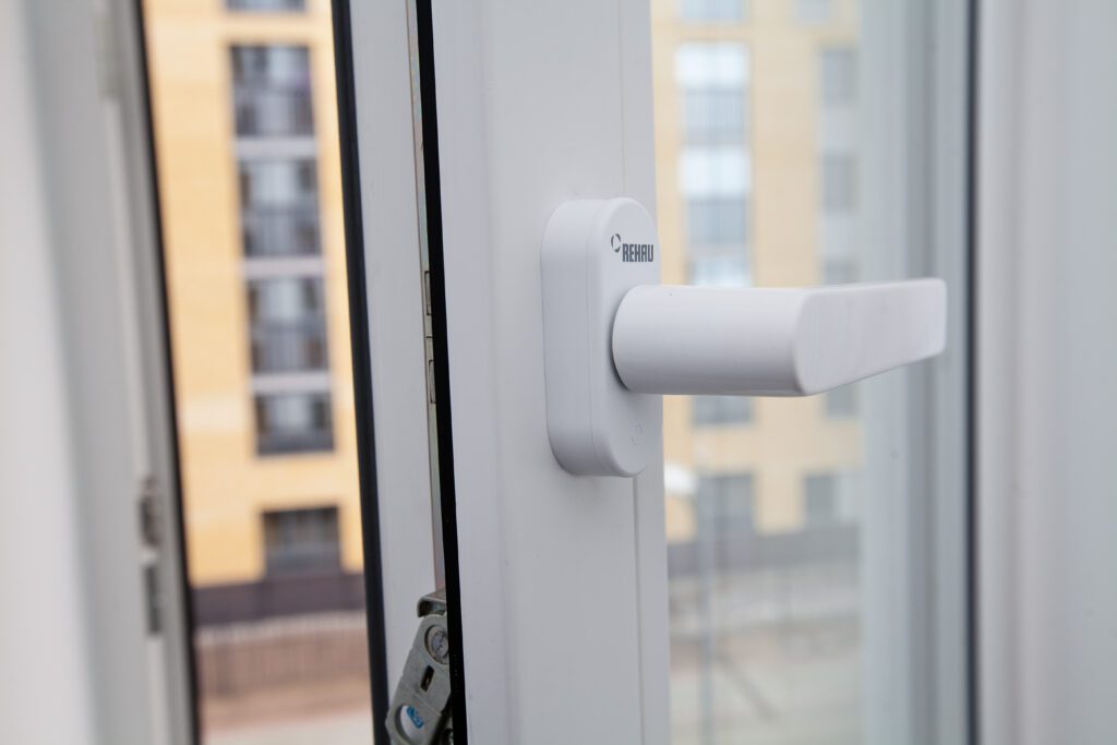 Detail kliky a kování na moderním bílém plastovém okně.