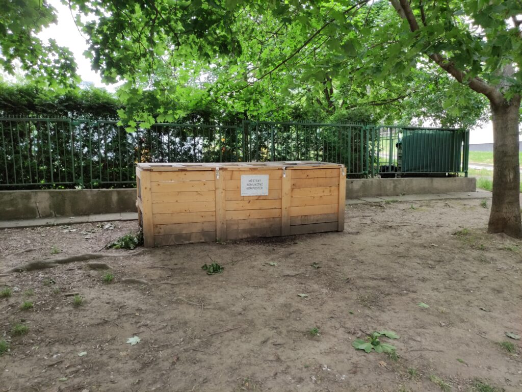 Dřevěný komunitní kompostér pod stromy v pražském Žižkově.