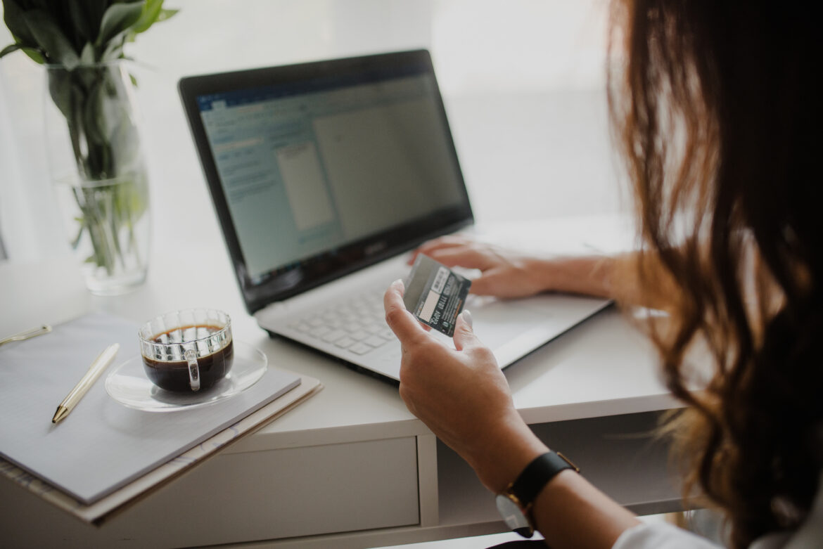 Ruce zadávají číslo platební karty do formuláře e-shopu na notebooku