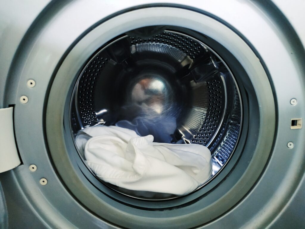 Malá náplň bílého prádla v bubnu pračky.