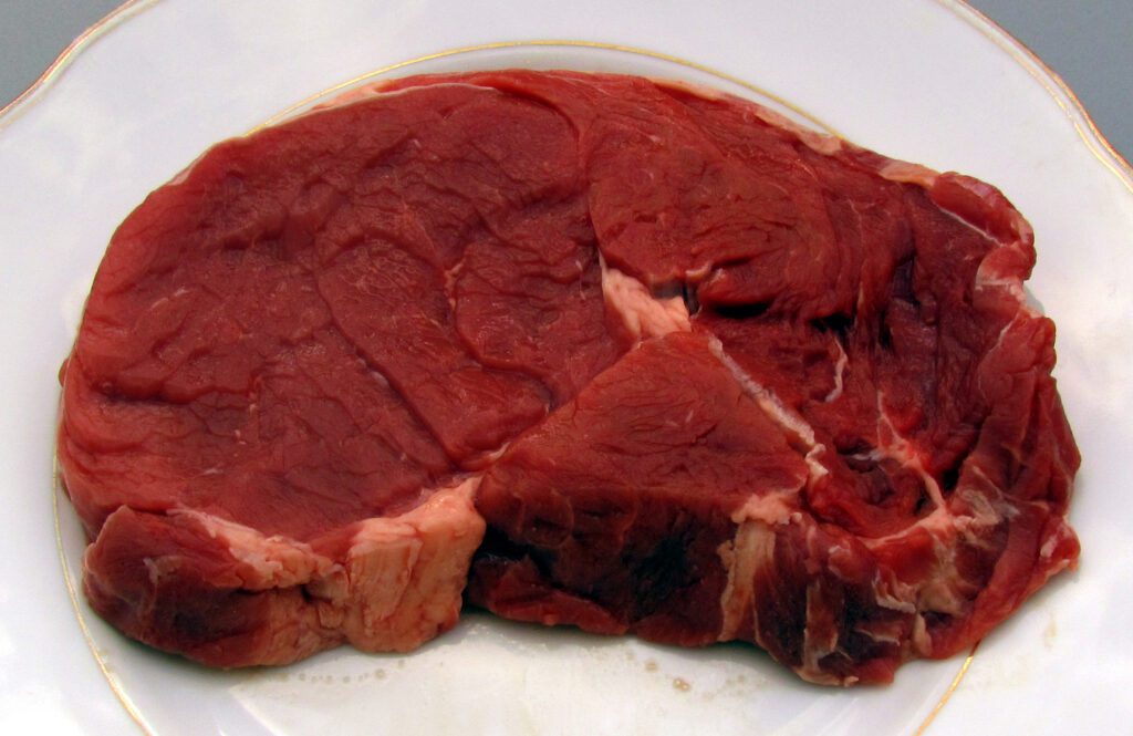 Syrový hovězí entrecôte položený na bílém talíři.