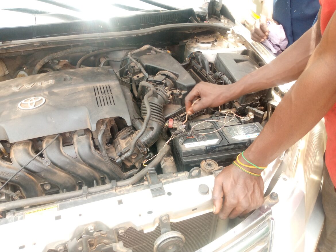 Mechanik kontroluje autobaterii pod otevřenou kapotou vozu