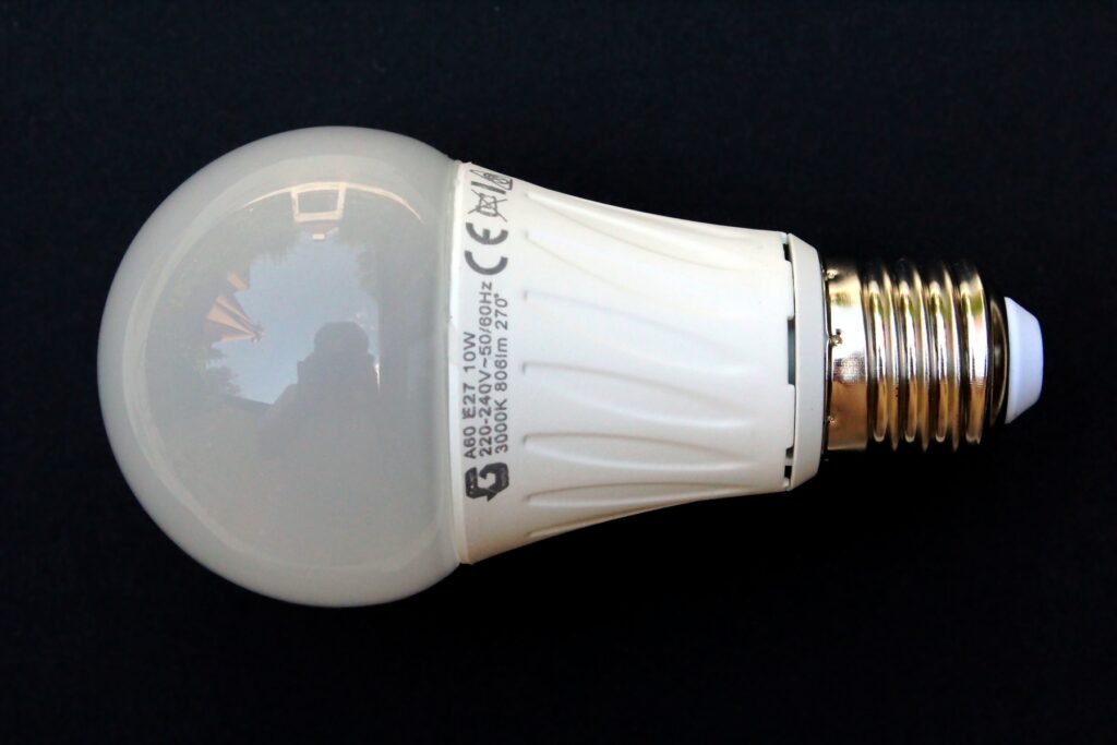 Bílá LED žárovka se závitem E27 a potiskem 10 W, 806 lm a 3000 K na tmavém podkladu.