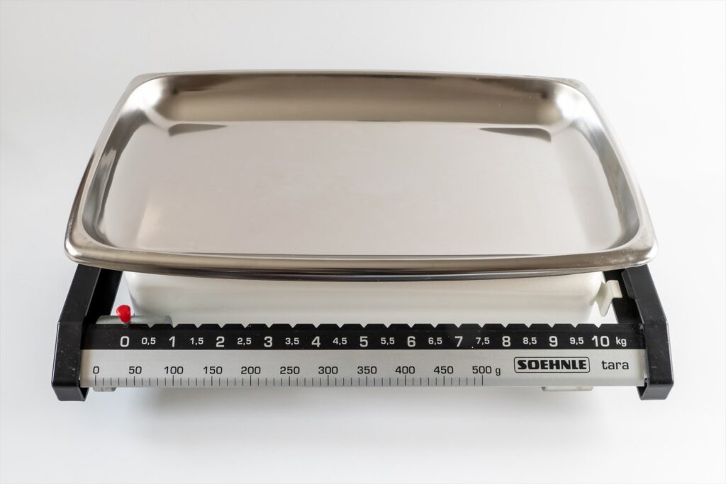Mechanická kuchyňská váha s kovovou miskou a stupnicí do deseti kilogramů.