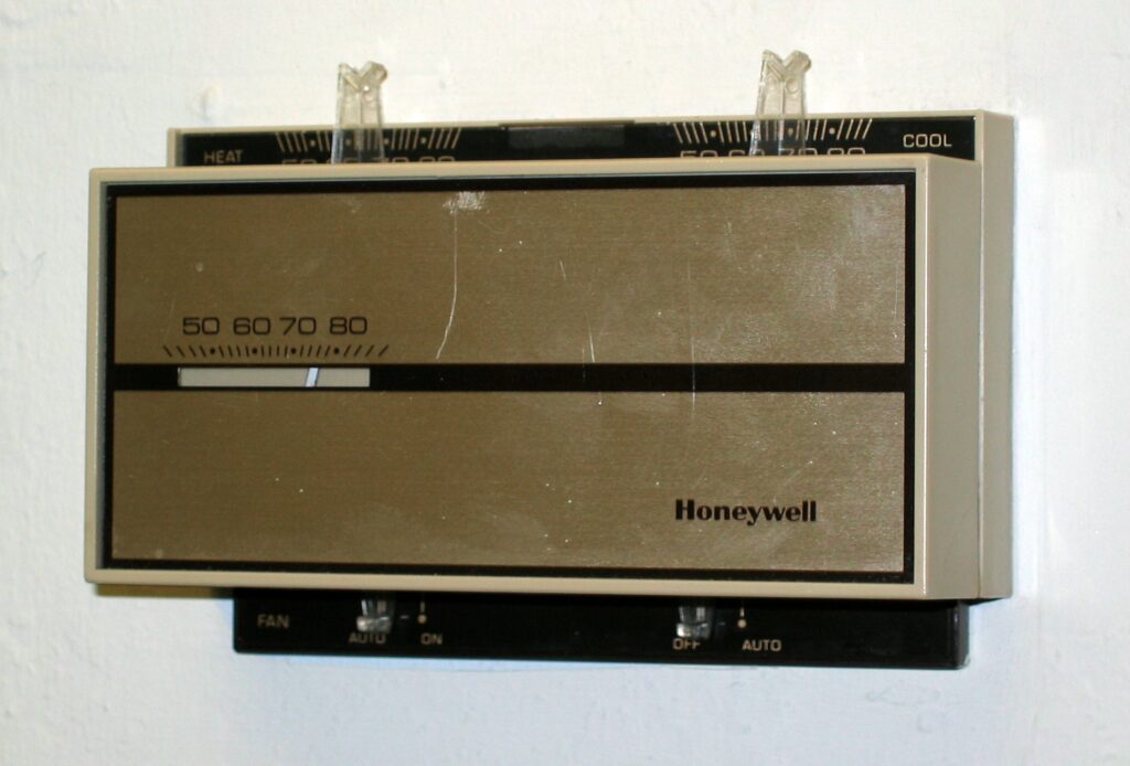 Obdélníkový nástěnný termostat Honeywell s posuvnými ovladači a stupnicí