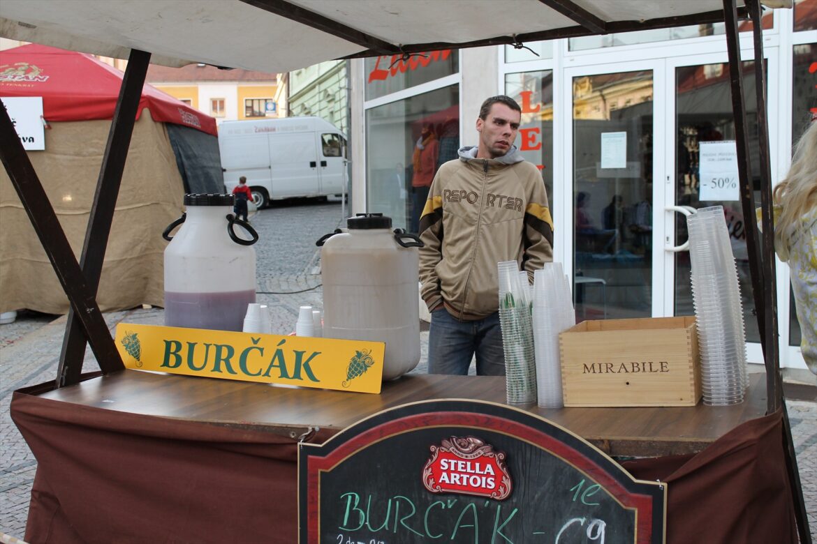 Stánek s nápisem Burčák, dvěma plastovými nádobami a kelímky