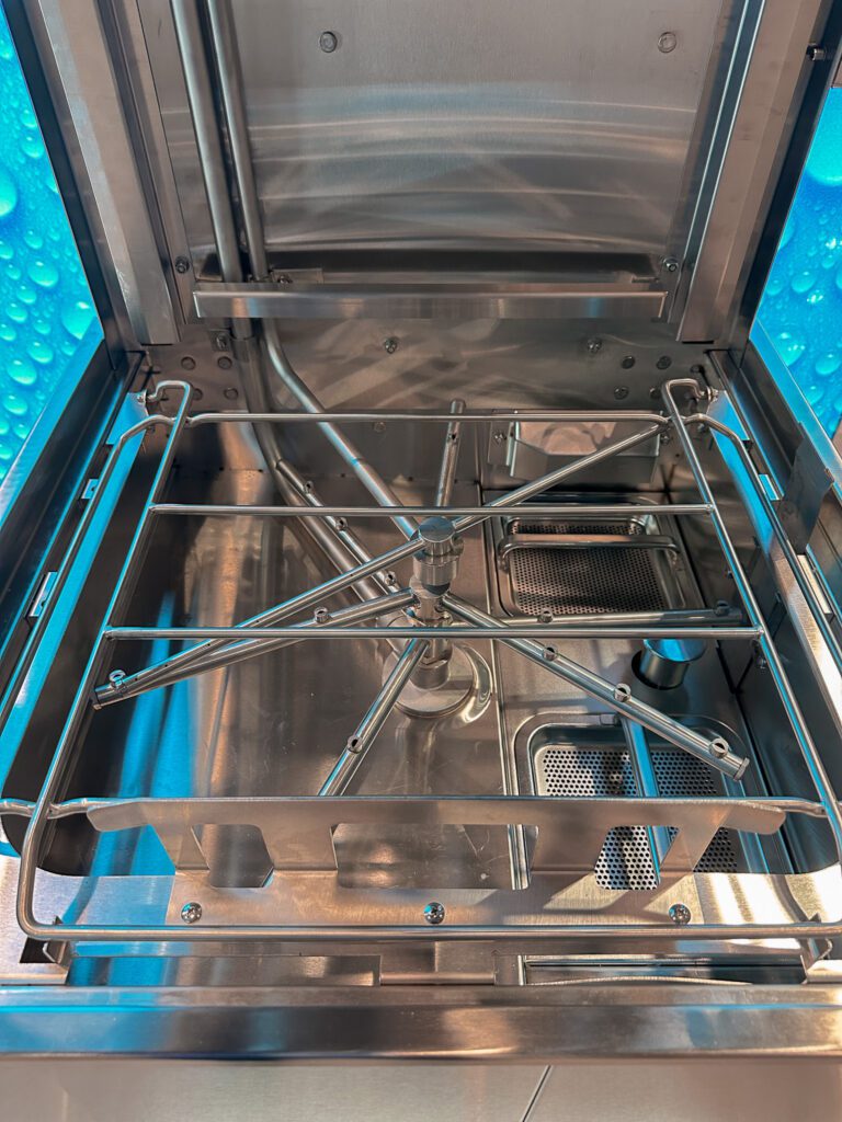 Detail ostřikovacích ramen myčky s tryskami, které se snadno ucpávají zbytky jídla