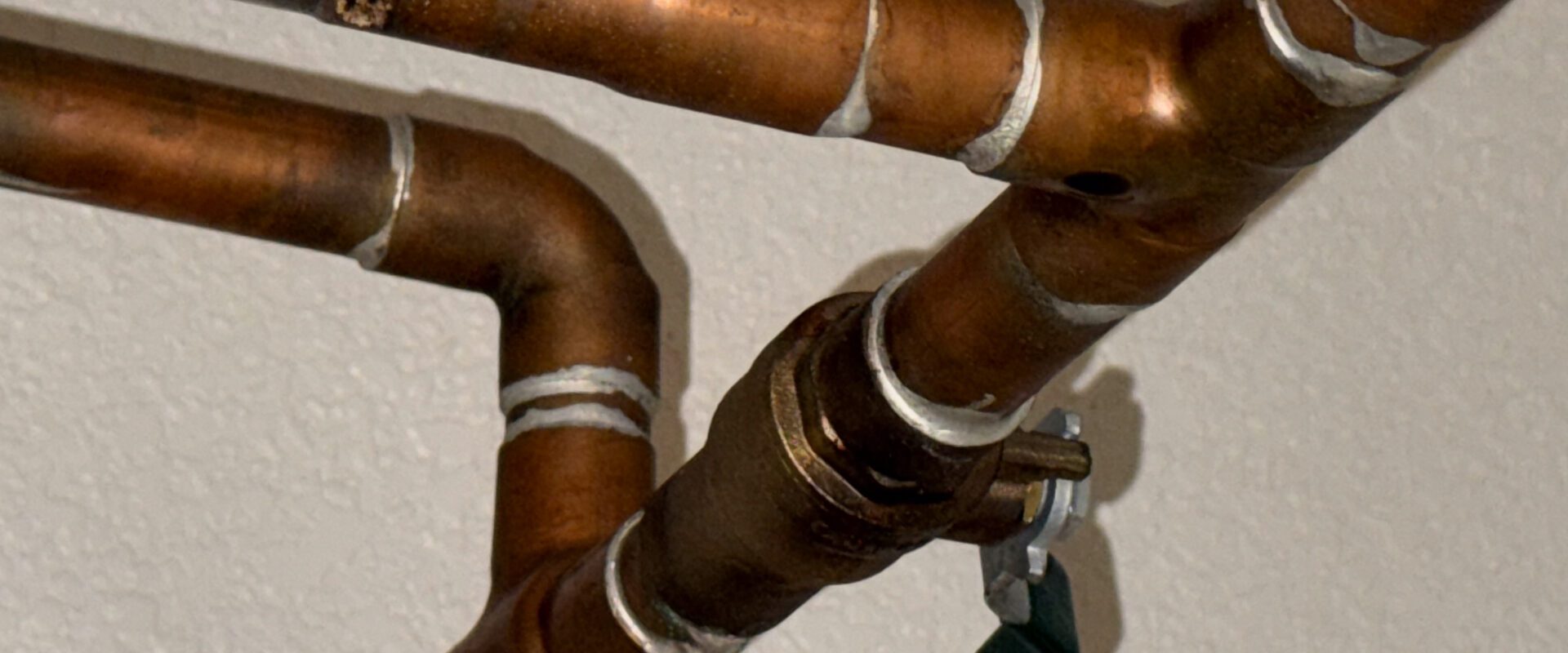 Elektrický zásobníkový ohřívač vody v technické místnosti s připojeným měděným potrubím.