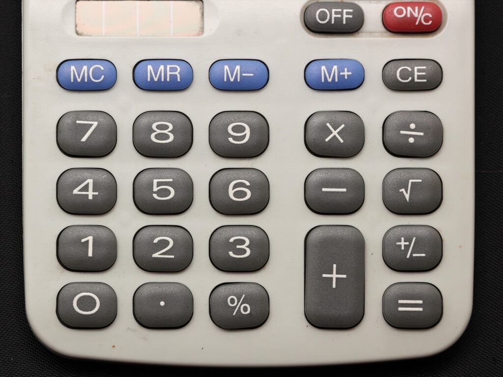 Detail číselných tlačítek a matematických funkcí stolní kalkulačky.