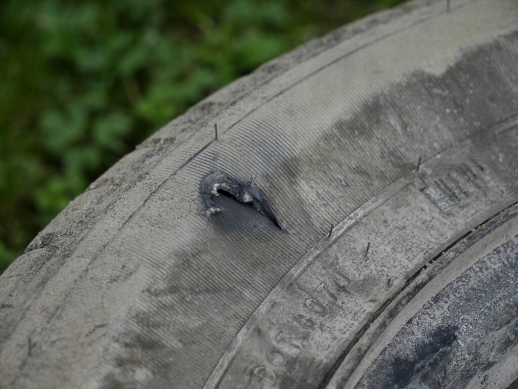 Detail otvoru v bočnici automobilové pneumatiky s viditelnými vlákny výztuže