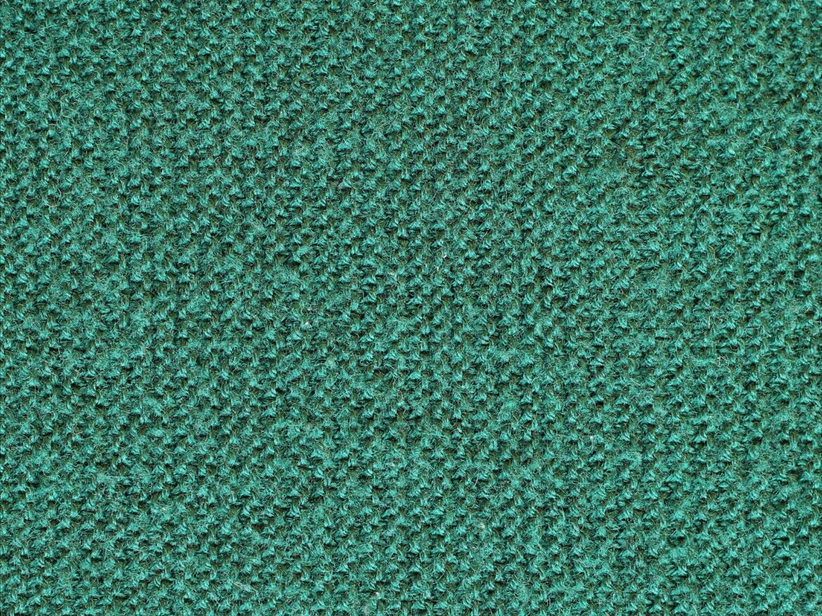 Detail zeleného vlněného úpletu s viditelnými oky.