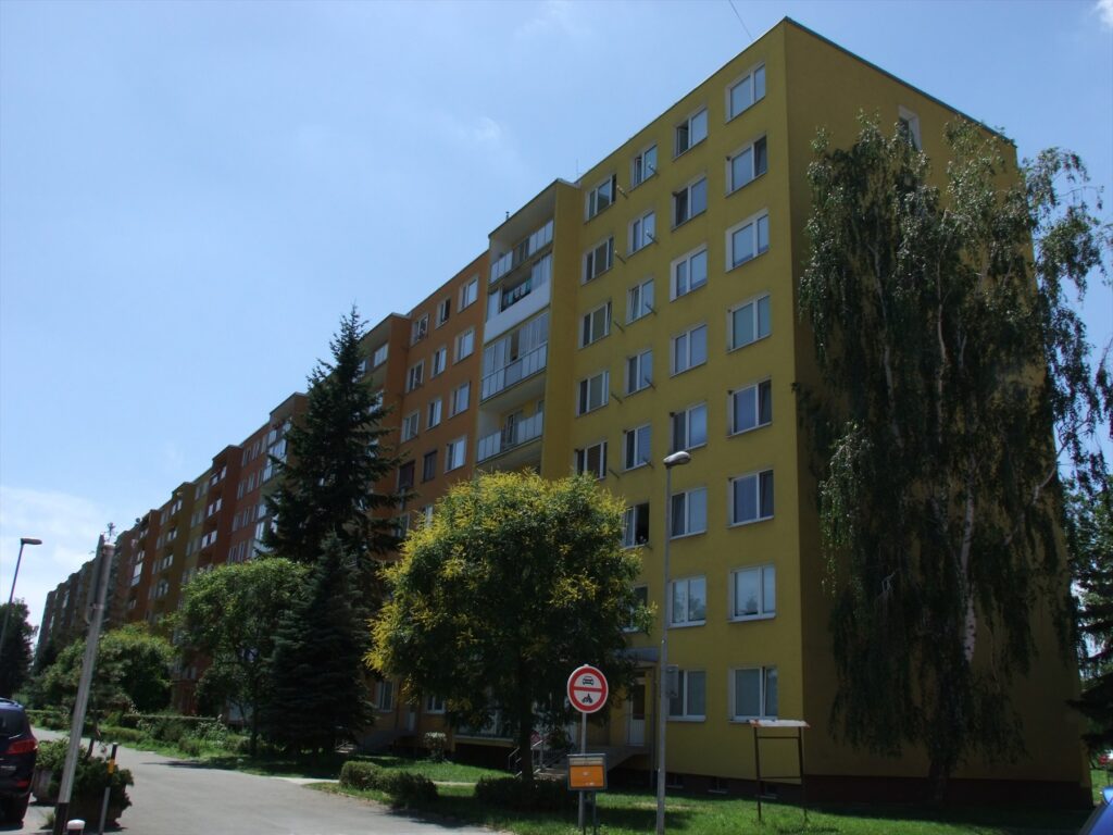 Celkový pohled na vícepatrový panelový bytový dům s řadami oken a balkonů