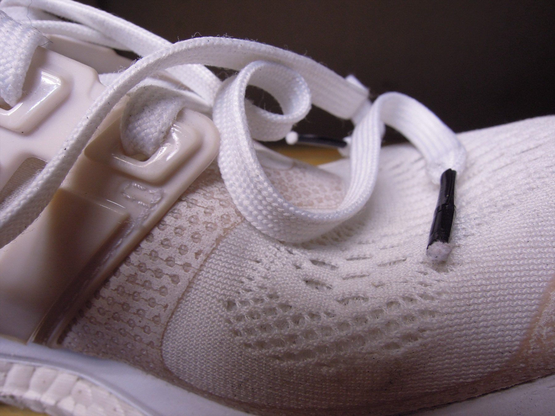 Detail bílé sportovní boty s očkem ploché tkaničky a černou koncovkou