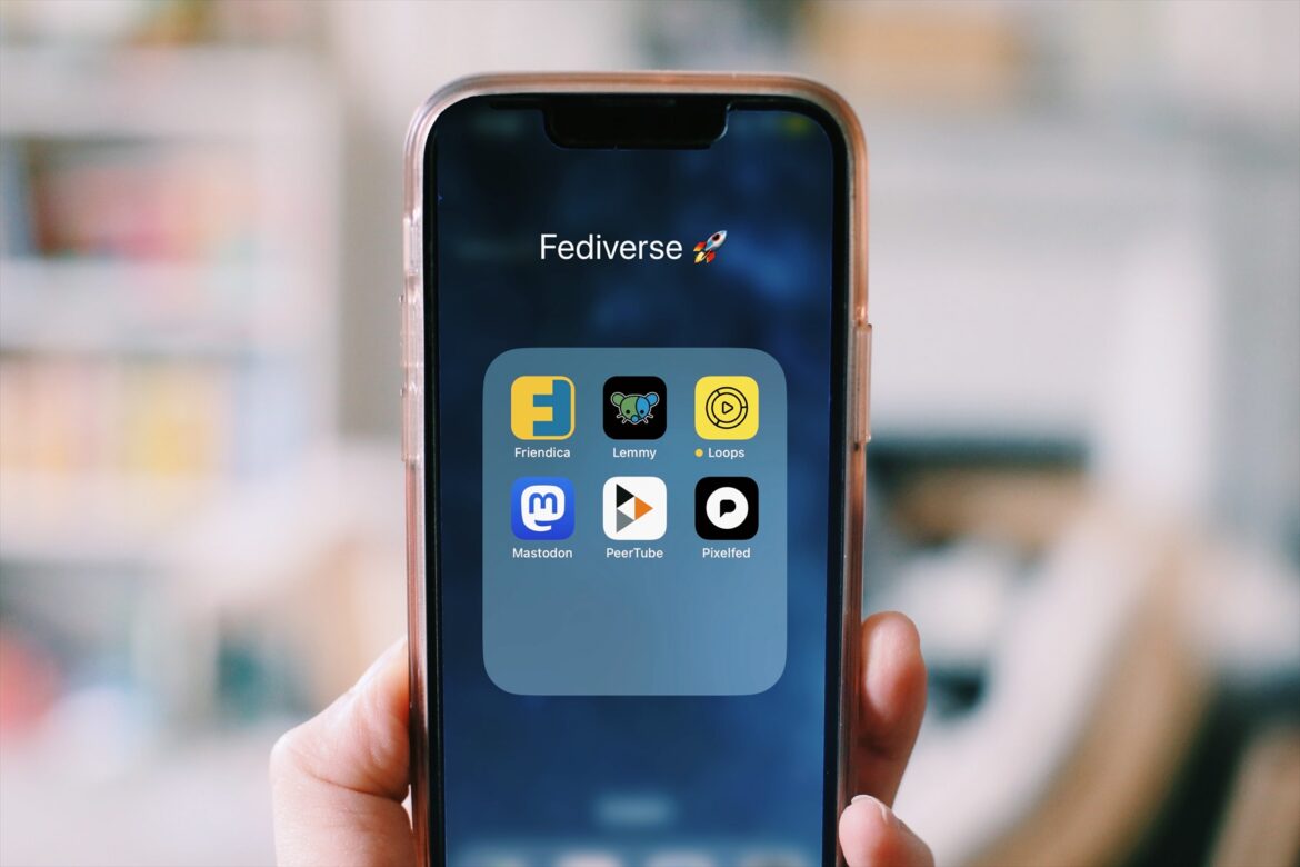 Ruka držící chytrý telefon s ikonami internetových aplikací na displeji.