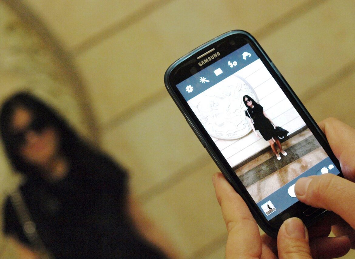 Ruce držící mobilní telefon při fotografování.