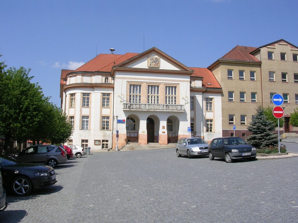 Budova České spořitelny na náměstí v Pacově s auty před vchodem.