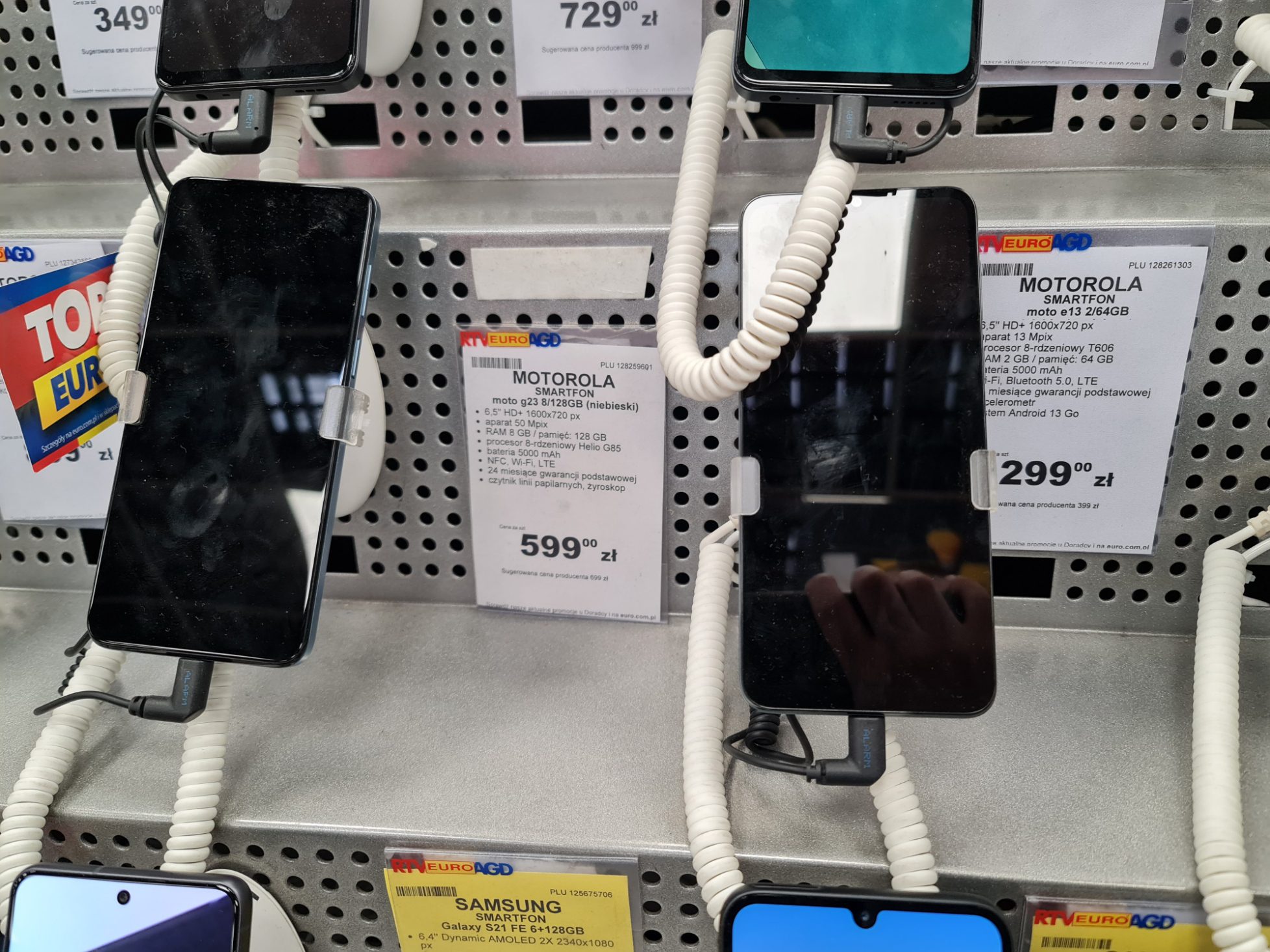 Telefony Motorola na prodejním stojanu s cenovkami v polských zlotých