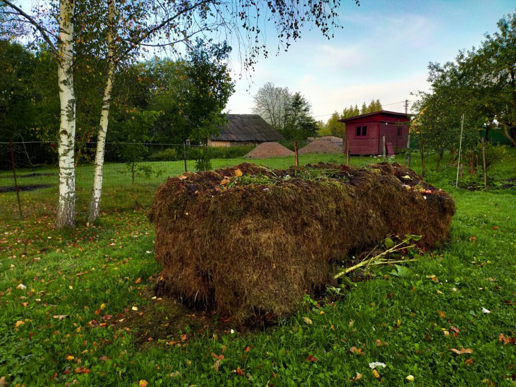 Velká hromada zahradního rostlinného materiálu vedle plotu.