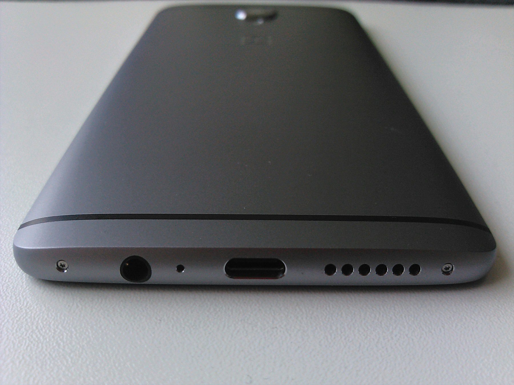 Spodní hrana telefonu OnePlus 3 s konektorem USB-C, zdířkou pro sluchátka a otvory reproduktoru