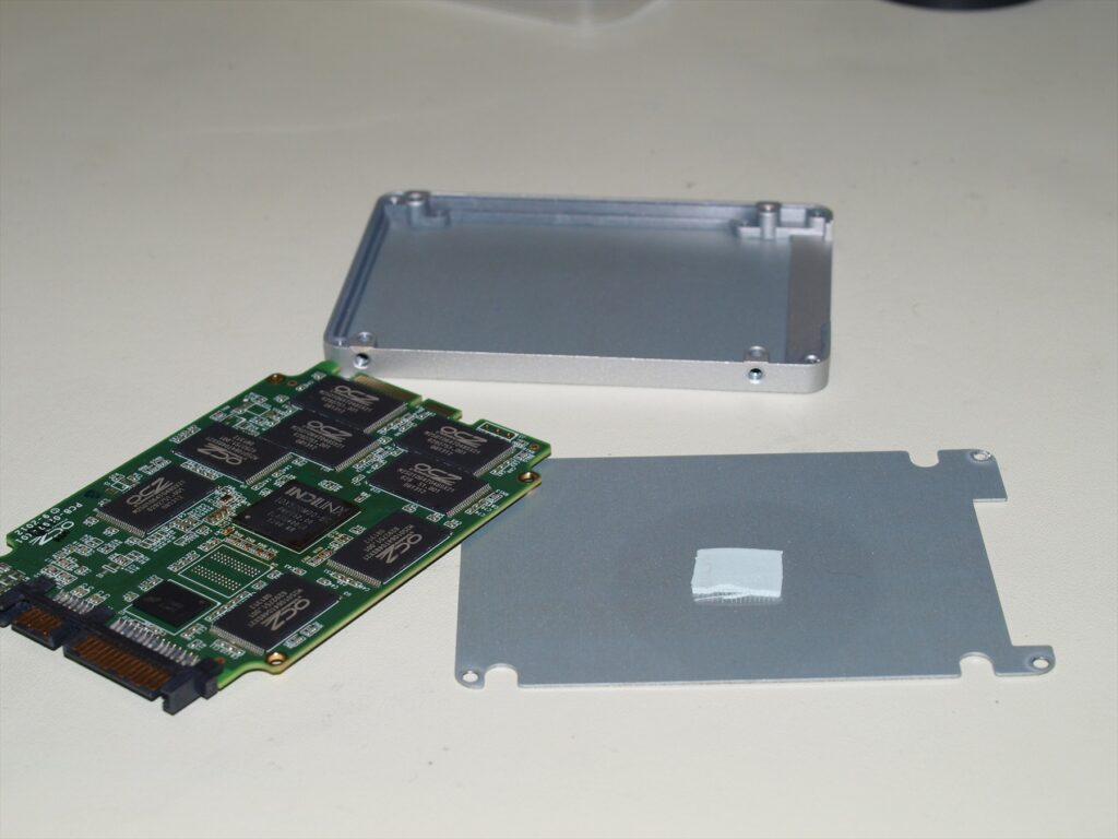 Rozebraný SSD OCZ s odkrytou deskou a částmi kovového pouzdra