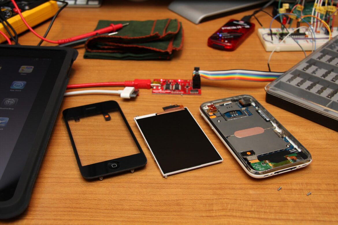 Rozebraný iPhone s odděleným displejem na stole vedle měřicí techniky