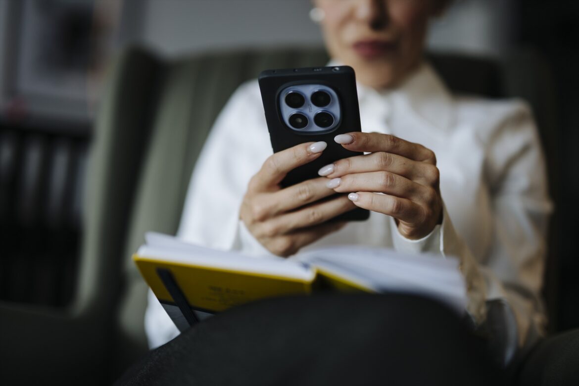 Žena držící chytrý telefon nad otevřenou knihou