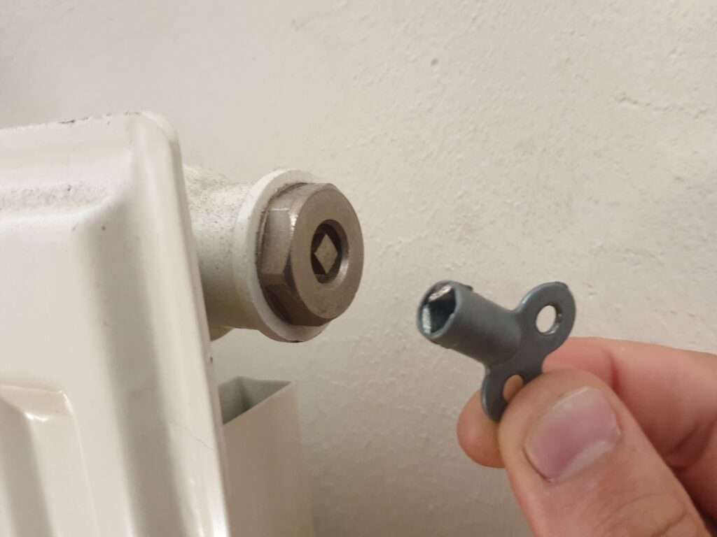 Odvzdušňovací ventil na boku radiátoru se zasunutým čtyřhranným klíčkem