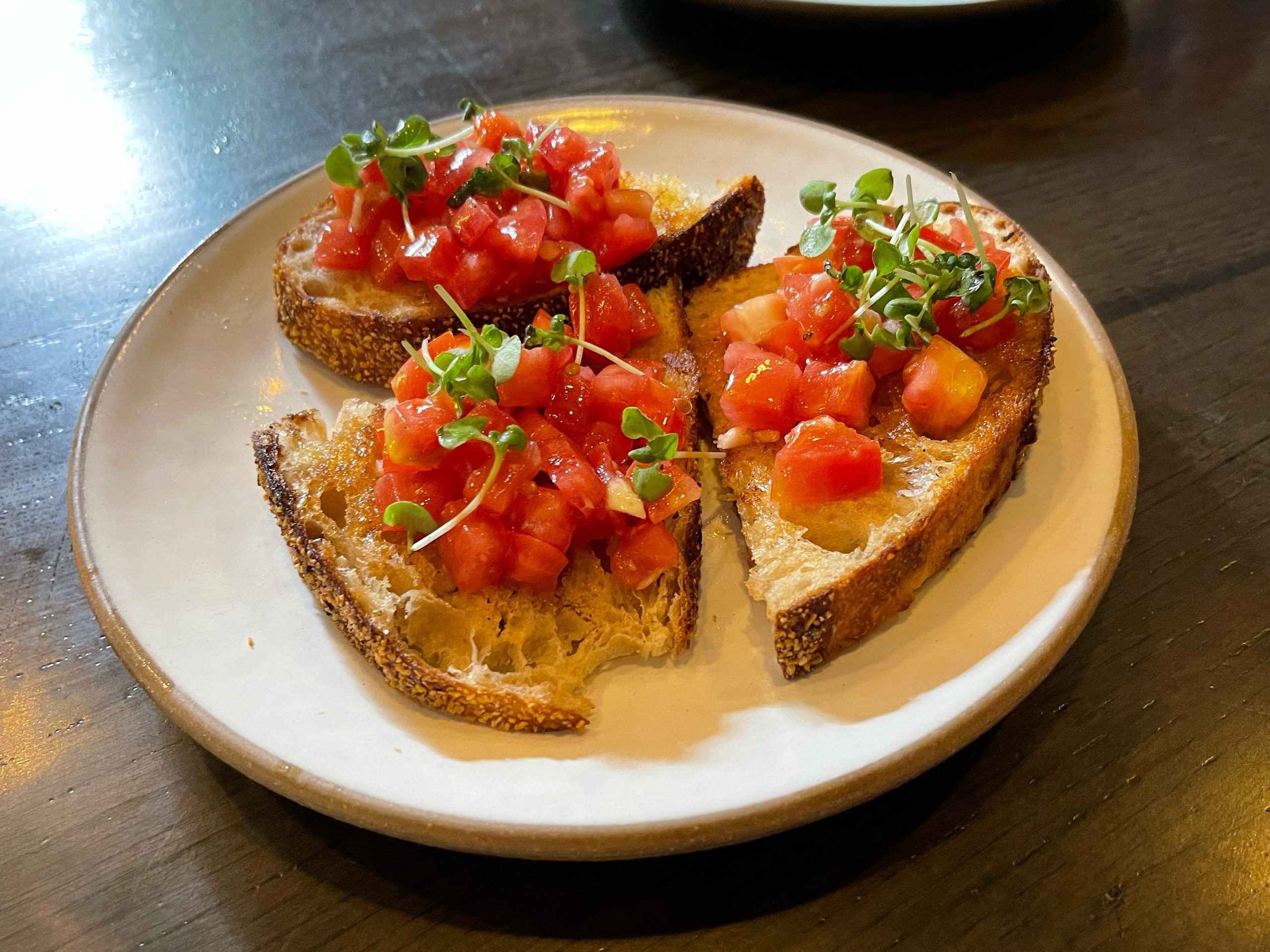 Opečený italský chléb bruschetta s rajčaty a bylinkami na talíři