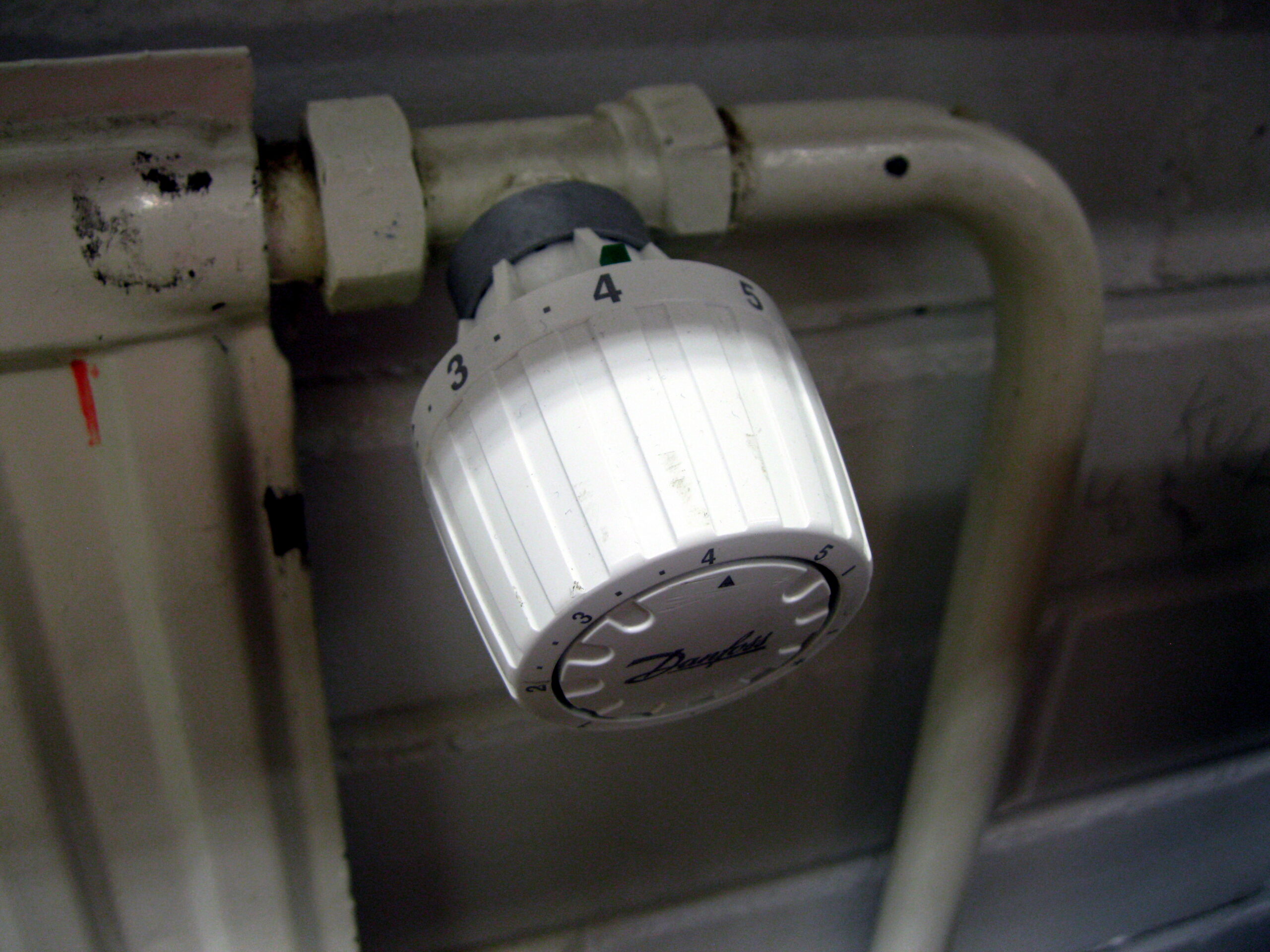 Detailní pohled na termostatickou hlavici Danfoss s vyznačenými číslicemi jedna až pět namontovanou na radiátoru