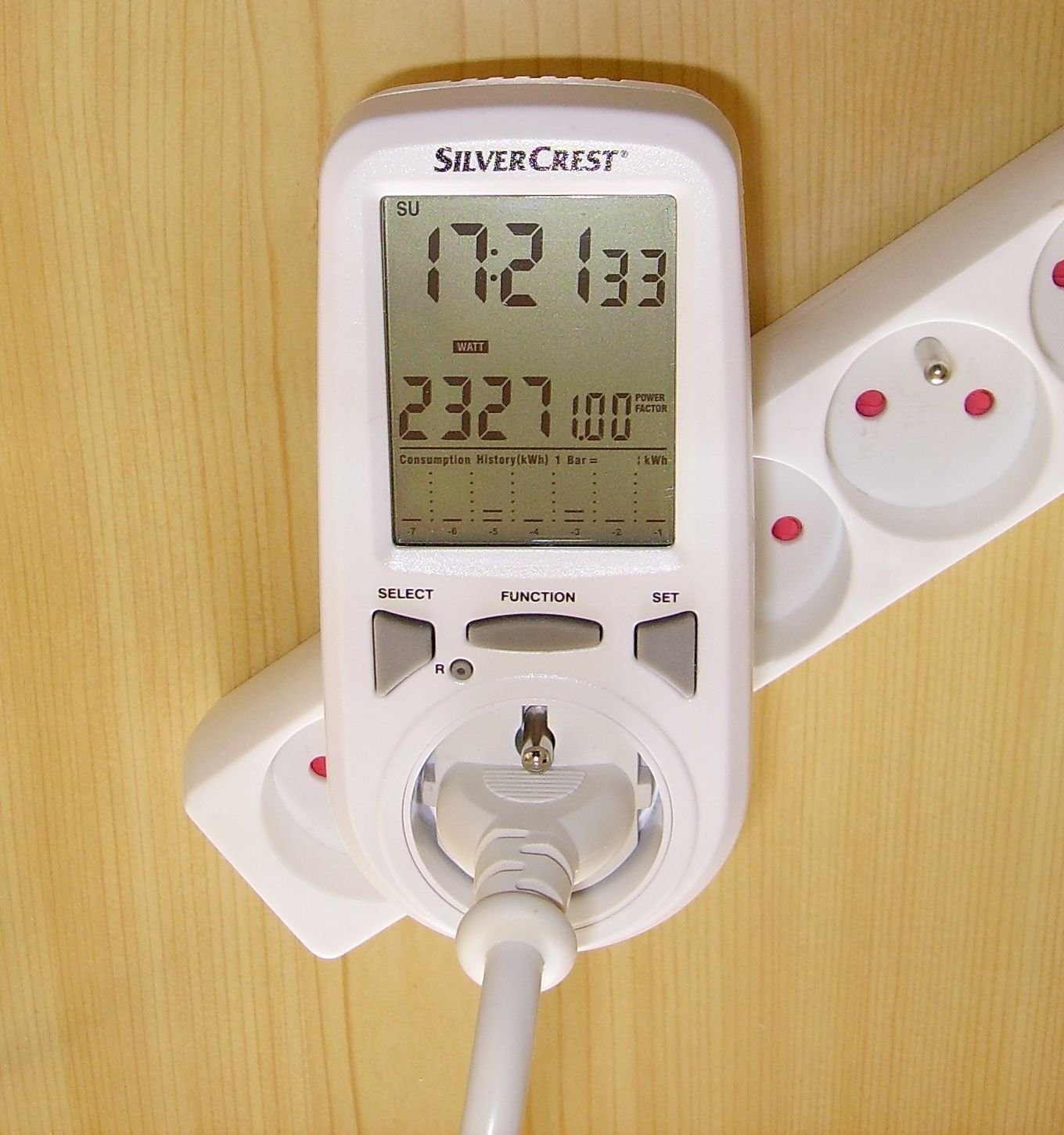 Zásuvkový měřič spotřeby elektrické energie zapojený v elektrické zásuvce.