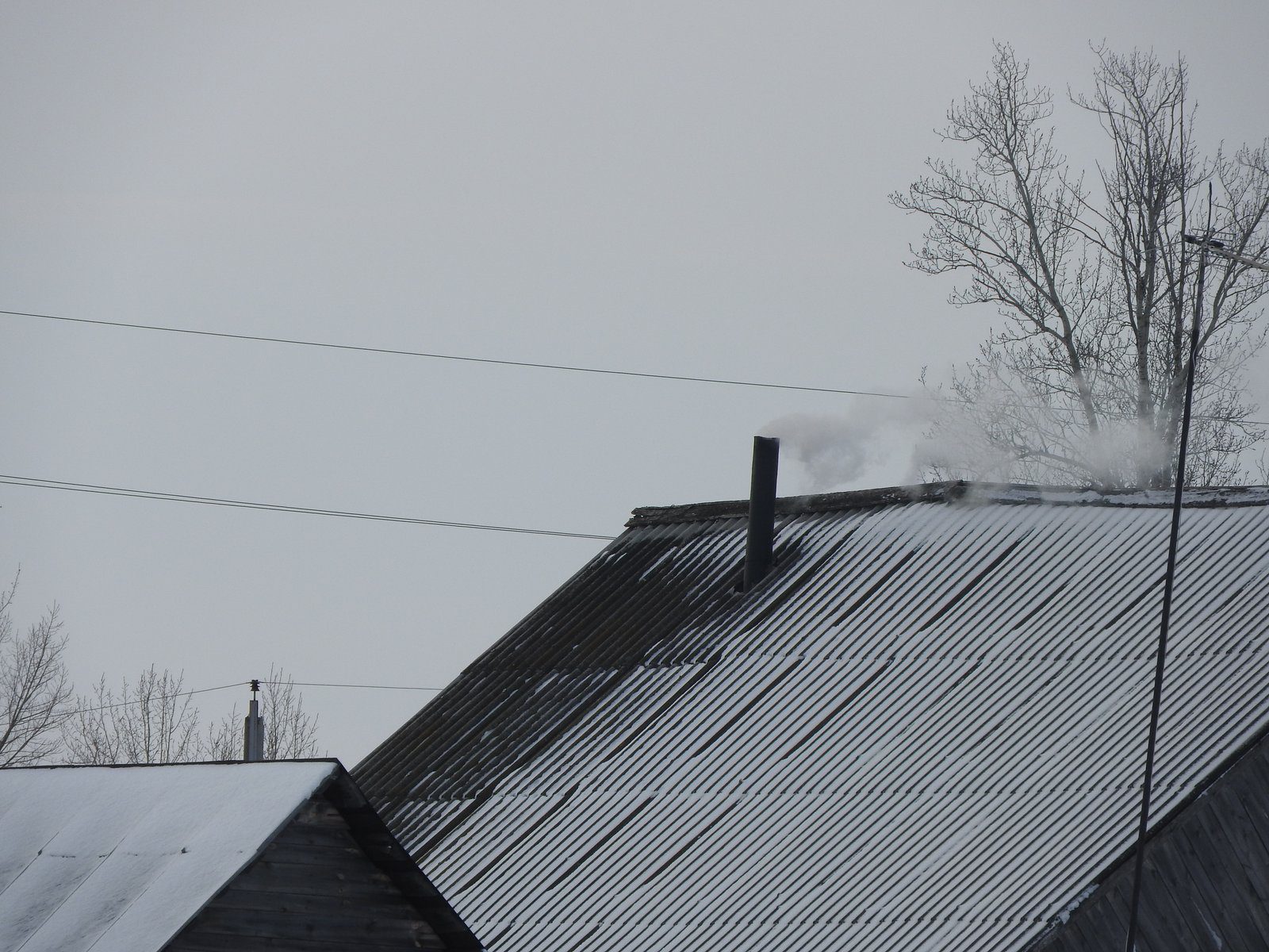Cihlový komín vyvedený nad hřeben střechy rodinného domu.