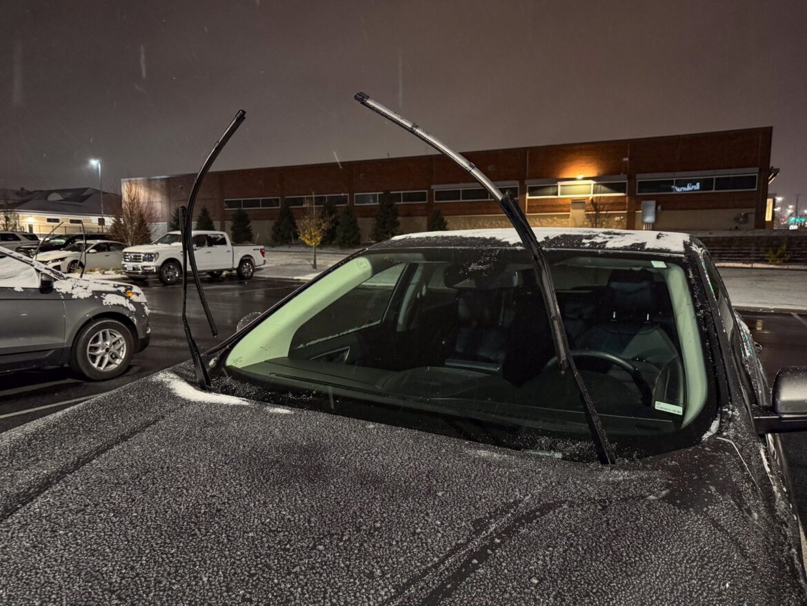 Zaparkované osobní auto se zvednutými ramínky stěračů nad namrzlým čelním sklem.